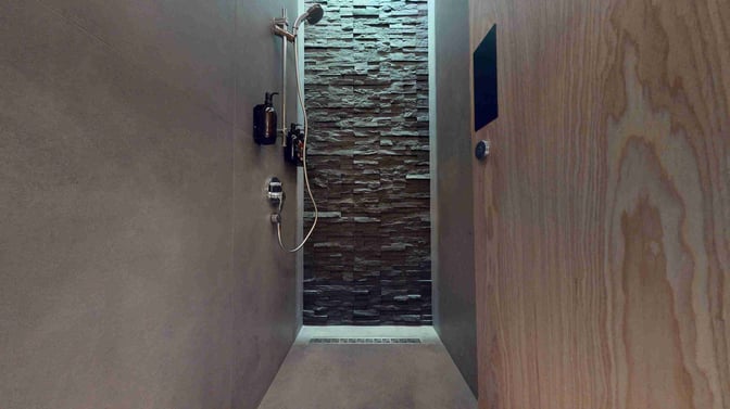 The shower facility at Dubai International Airport's Sleepover Lounge in Concourse B features a wall-mounted showerhead and toiletries.