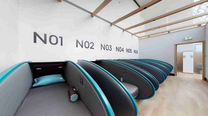 The Sleepover Lounge at Dubai International Airport's Concourse B features individual sleeping pods with pillows and blankets for passenger rest.