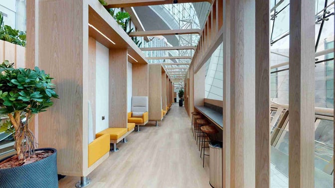 Seating pods and a counter with stools provide semi-private spaces for relaxation at the Sleepover Lounge in Dubai International Airport Concourse B.