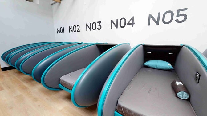 Sleeping pods at Dubai International Airport's Sleepover Lounge in Concourse B offer individual resting spaces with bedding and privacy dividers.