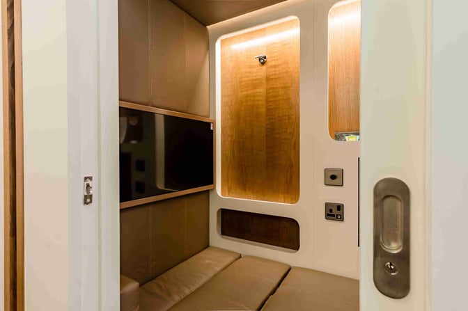 The sleep pod at Dubai International Airport's Concourse C features a cushioned bench, television, and power outlets for passenger comfort.