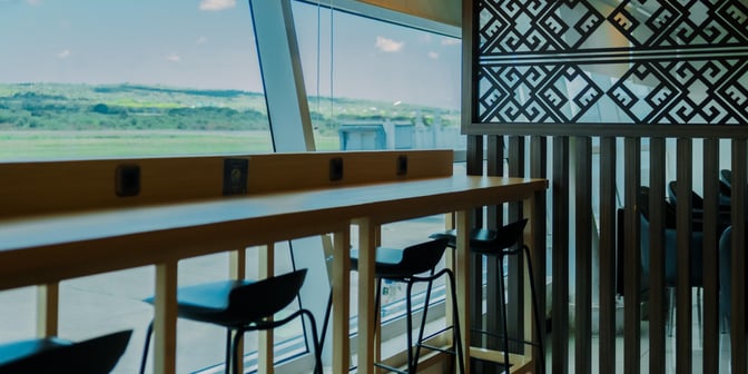 The Concordia Lounge at El Tari Airport features a high counter with bar stools, offering views of the runway through large windows.