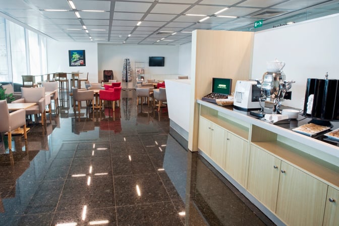 The Primeclass Lounge at Esenboğa International Airport features a seating area with tables and a self-serve beverage station.