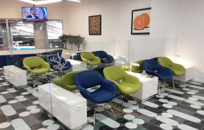 The seating area in the CIP Lounge at Faro International Airport features comfortable chairs with individual tables and a view of the terminal.