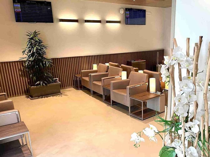The seating area in the VIP Club Lounge at Florence Airport features armchairs with side tables and a flight information screen.