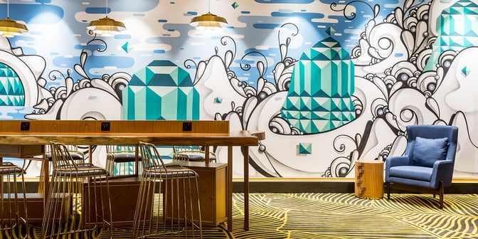 The Plaza Premium Lounge at Rio de Janeiro–Galeão International Airport features a seating area with high stools and a decorative mural.