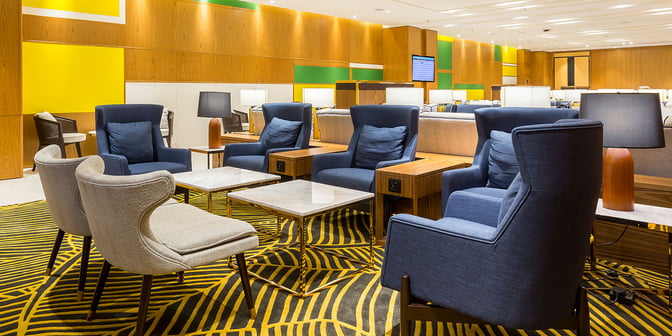 The seating area in Plaza Premium Lounge at Rio de Janeiro Airport features comfortable chairs and tables with accessible power outlets.
