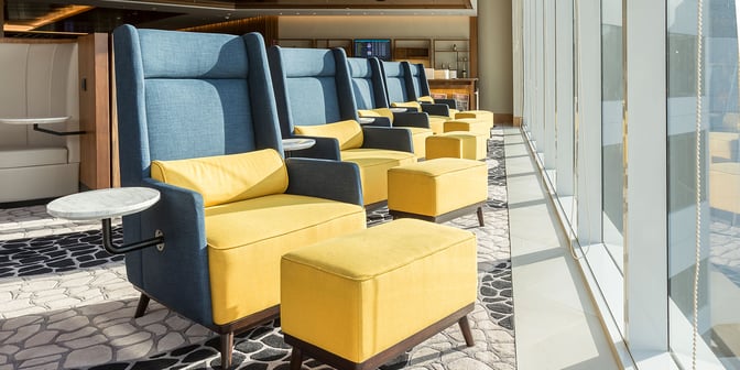 Seating area in the Plaza Premium Lounge at Rio de Janeiro–Tom Jobim Airport features comfortable chairs with side tables and ottomans.