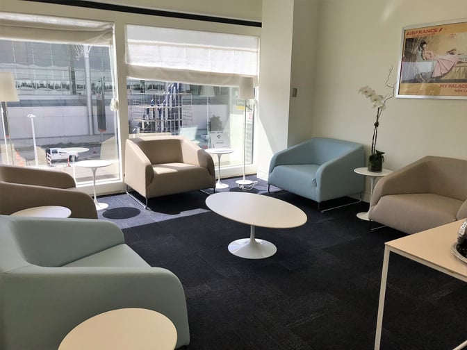 The seating area in the Air France Lounge at George Bush Intercontinental Airport features armchairs and tables with views of the tarmac.