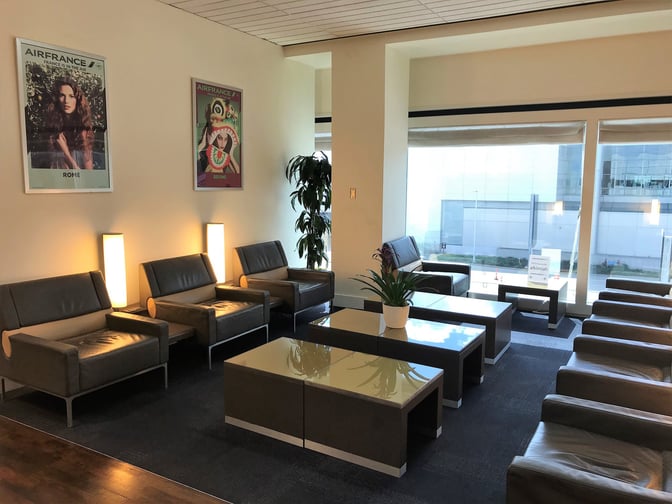 The Air France Lounge at George Bush Intercontinental Airport features a seating area with armchairs and tables, offering airport views.