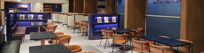 The seating area in N Sky Hub Lounge at Gimhae International Airport features tables and chairs with semi-private booth options.