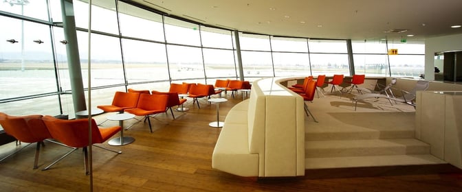 The VIP Lounge at Graz Airport features spacious seating areas with individual tables, offering panoramic views of the runway.