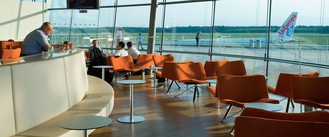 The VIP Lounge at Graz Airport features seating with tables and large windows offering views of the runway and aircraft.