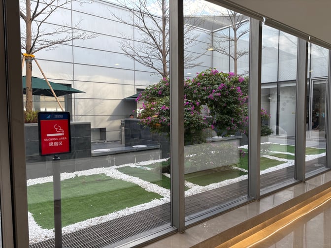 The China Southern Lounge at Guangzhou Airport features a designated smoking area with outdoor seating and landscaped greenery visible through large windows.