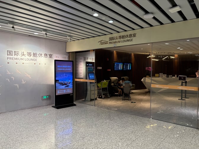The entrance to the Premium Lounge at Guangzhou Baiyun International Airport features a reception desk and seating area with flight information displays.