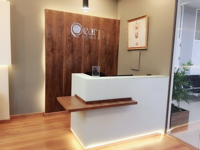 The reception area of Pearl Lounge at Hassan I Airport features a check-in desk with adjacent seating visible through glass partitions.