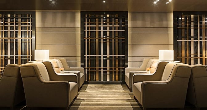 The seating area in Plaza Premium Lounge near Gate 35 at Hong Kong International Airport features armchairs and small tables with lamps.