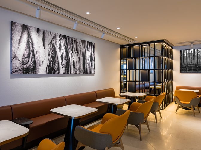 The seating area in Plaza Premium Lounge near Gate 60 at Hong Kong International Airport features tables and chairs for dining.