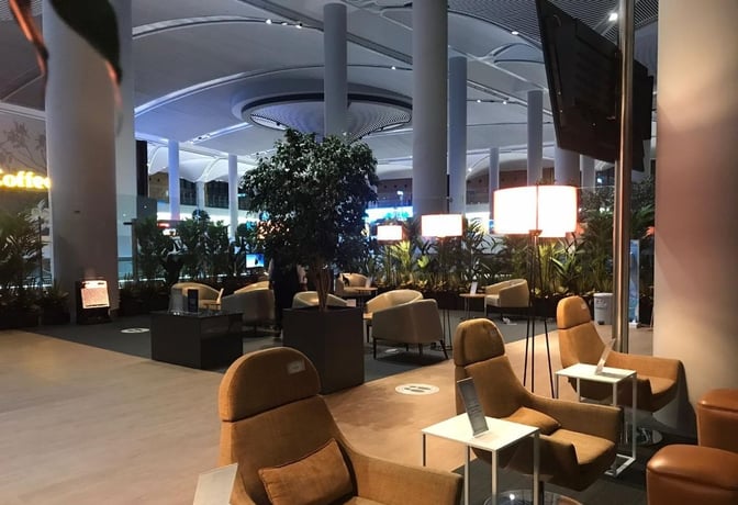 The IGA Lounge at Istanbul Airport features a seating area with armchairs and small tables, surrounded by plants for privacy.