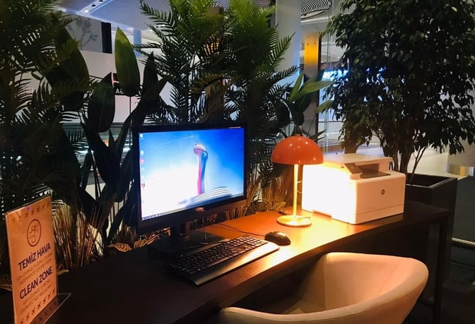 The IGA Lounge at Istanbul Airport features a workstation with a computer and printer, surrounded by plants for privacy.