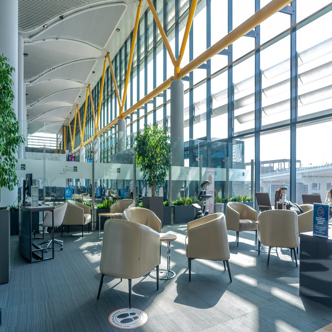 The IGA Lounge at Istanbul Airport features a seating area with armchairs and tables, offering views of the tarmac through large windows.