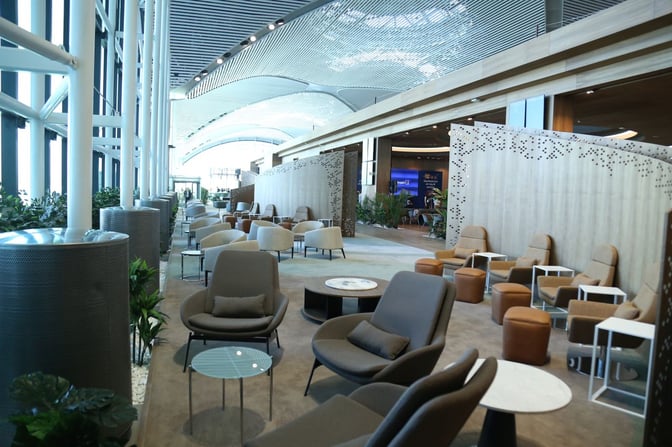 The IGA Lounge at Istanbul Airport features a spacious seating area with armchairs and small tables, offering a comfortable waiting environment.