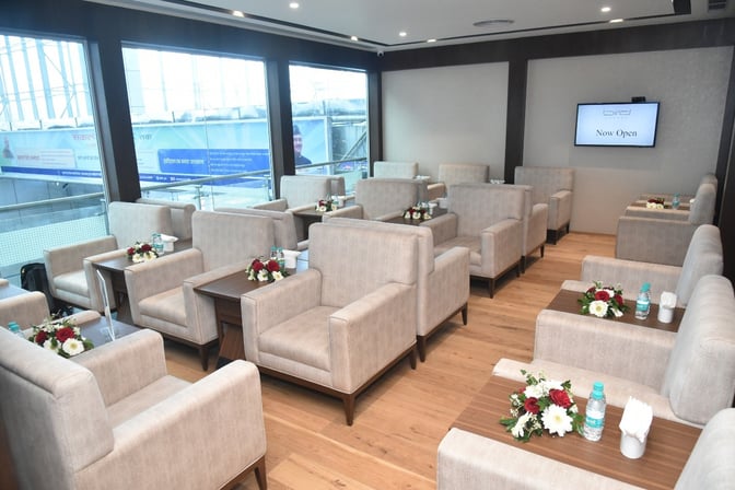The Bird Lounge at Jolly Grant Airport features comfortable seating with individual tables, offering a relaxing space for travelers.