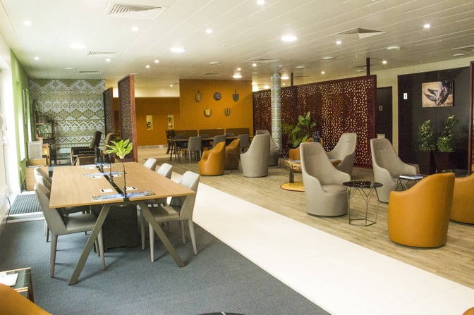 The Twiga Lounge at Julius Nyerere International Airport features a seating area with armchairs, tables, and decorative partitions for privacy.