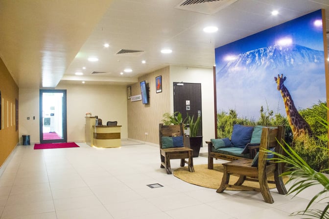 The Twiga Lounge entrance at Julius Nyerere International Airport features a reception desk and seating area with a nature-themed mural.