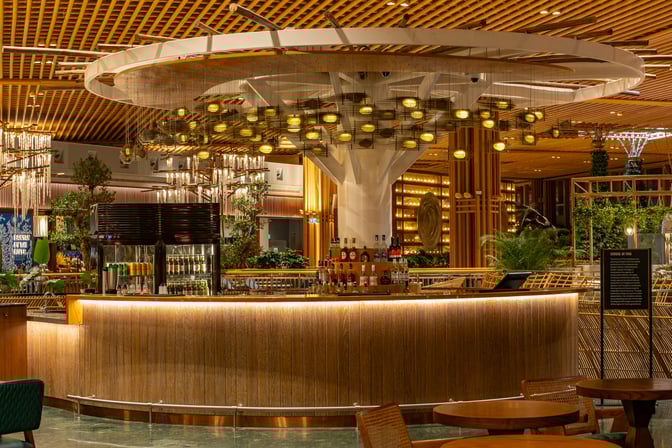 The bar area in the 080 International Lounge at Kempegowda Airport features a selection of spirits and a central seating arrangement.