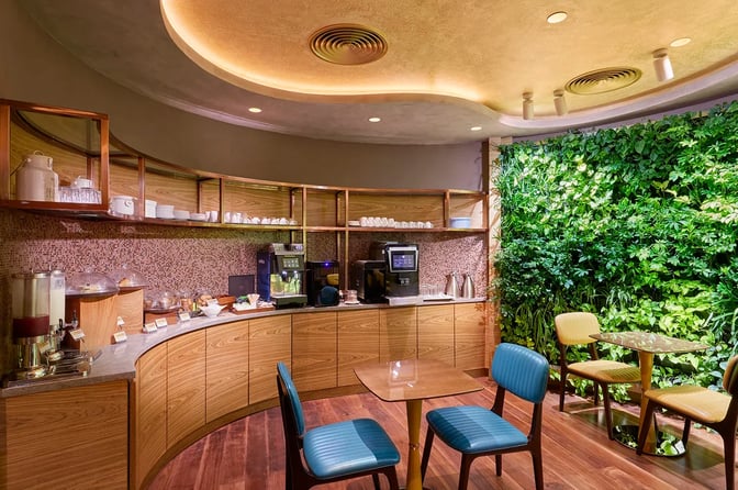 The lounge features a self-serve beverage and snack station with seating, adjacent to a vertical garden wall.