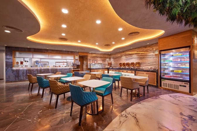 The 080 Domestic Lounge at Kempegowda Bangalore International Airport features a dining area with tables, chairs, and a self-serve beverage station.