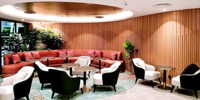 The seating area in the Travel Club Lounge at Kota Kinabalu International Airport features a mix of armchairs and a curved sofa with small tables.