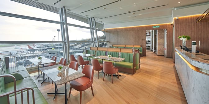 The seating area at Plaza Premium First Lounge in Kuala Lumpur International Airport offers booth and table seating with views of the tarmac.