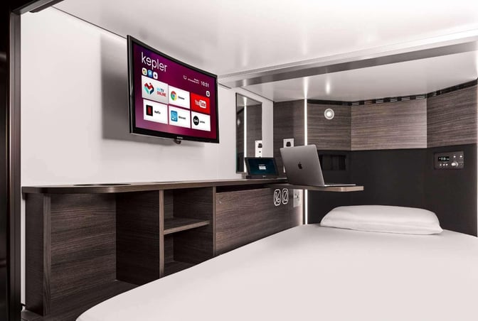 The Kepler Club at Kuala Lumpur International Airport features private sleeping pods with a bed, wall-mounted TV, and workspace.