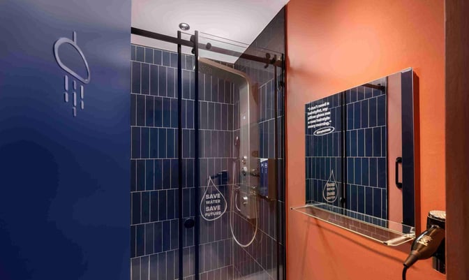 The shower facility at Kepler Club, Kuala Lumpur International Airport, features a glass enclosure and a mounted hairdryer for traveler convenience.