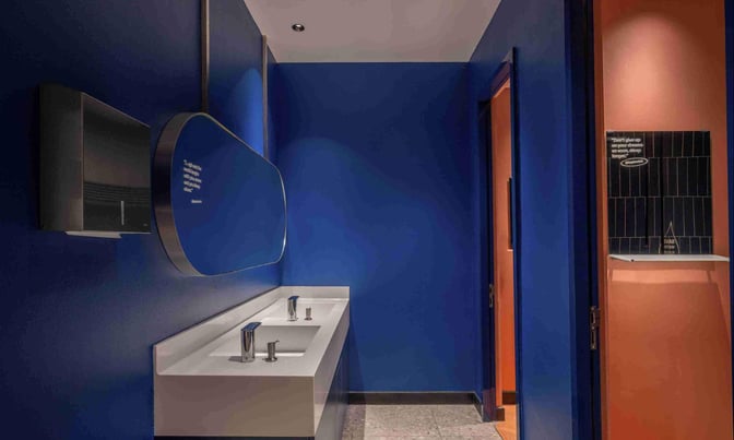 The restroom area in Kepler Club at Kuala Lumpur International Airport features a double sink with automatic faucets and a hand dryer.