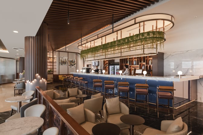 The Travel Club Lounge at Kuala Lumpur International Airport features a bar area with counter seating and adjacent lounge chairs.