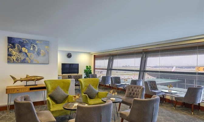 The Sky Suite Airport Lounge at Kuala Lumpur International Airport features comfortable seating with views of the runway through large windows.