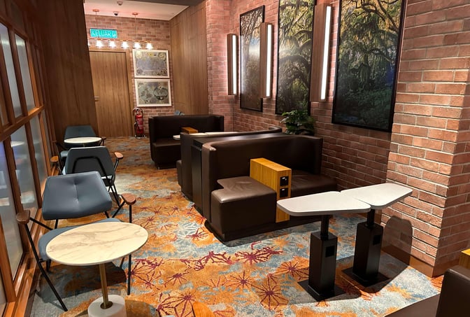 Seating area in the Travel Club Lounge at Kuala Lumpur International Airport features armchairs and tables, offering a comfortable waiting space.