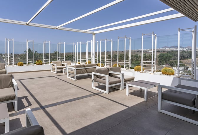 The outdoor seating area at Sala VIP Guacimeta features cushioned chairs and tables with views of the surrounding landscape.