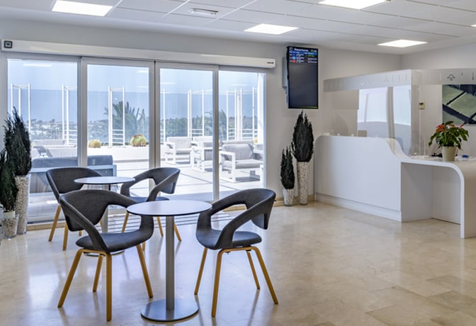 The Sala VIP Guacimeta at Lanzarote Airport features a seating area with tables and chairs, adjacent to a terrace with outdoor seating.