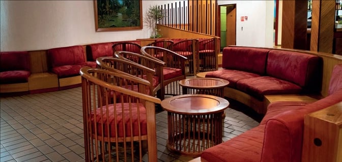 The seating area in Samba Lounge at Leon M'Ba International Airport features curved couches and round tables for passenger relaxation.