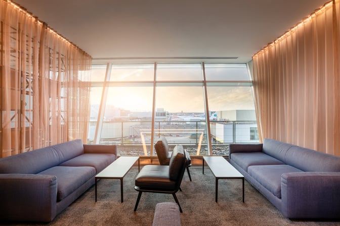 The Club Aspire Lounge at London Gatwick Airport features a seating area with sofas and chairs overlooking the airport runway.