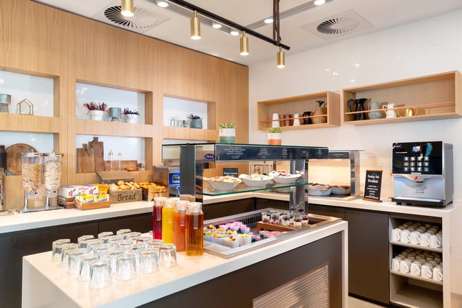 The Club Aspire Lounge at London Gatwick Airport features a self-serve breakfast station with cereals, pastries, juices, and a coffee machine.