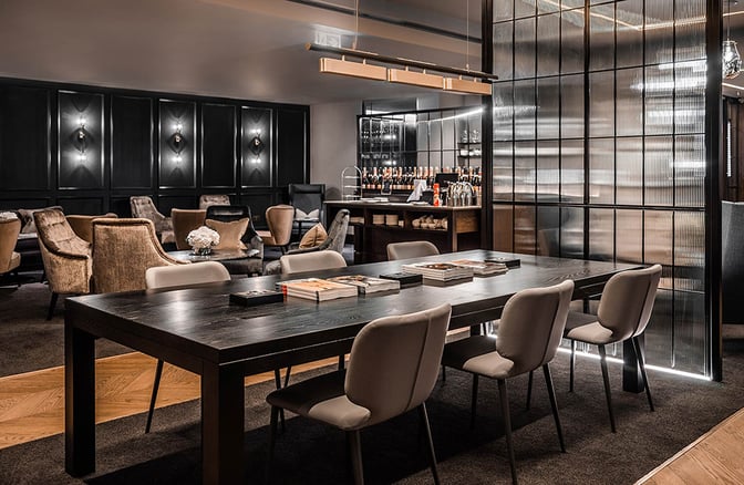 The No1 Lounge at London Luton Airport features a communal table with seating and a bar area offering various beverages.