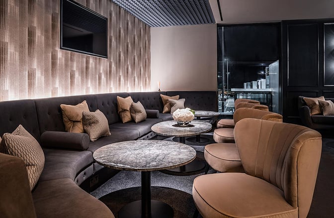 The No1 Lounge at London Luton Airport features a seating area with cushioned chairs, round tables, and a view of the tarmac.