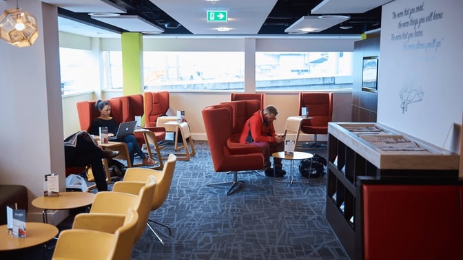 The seating area at the Escape Lounge, London Stansted, features comfortable chairs and tables for passengers to relax and work.