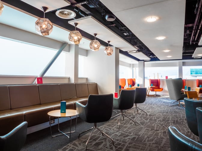 The seating area in the Escape Lounge at London Stansted Airport features comfortable chairs and tables, providing a relaxing space for travelers.
