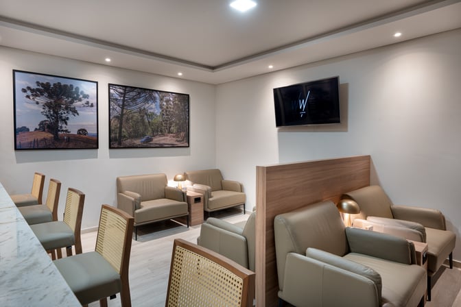 The seating area in W Lounge Londrina features comfortable chairs and a TV, providing a relaxing space for travelers.
